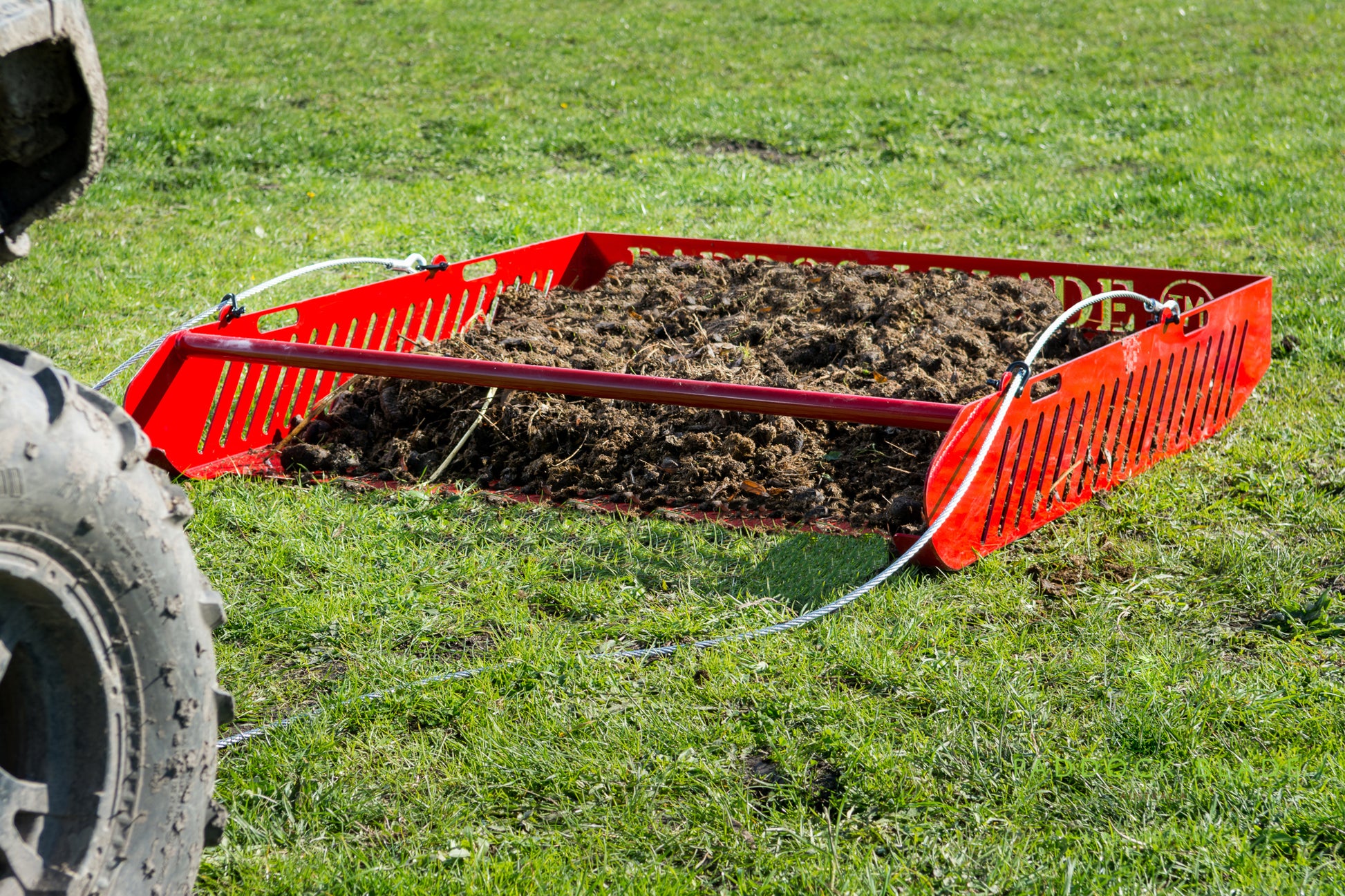 Red Paddock Blade horse paddock cleaner with sturdy handle, designed for efficient paddock maintenance by Paddock Blade UK.